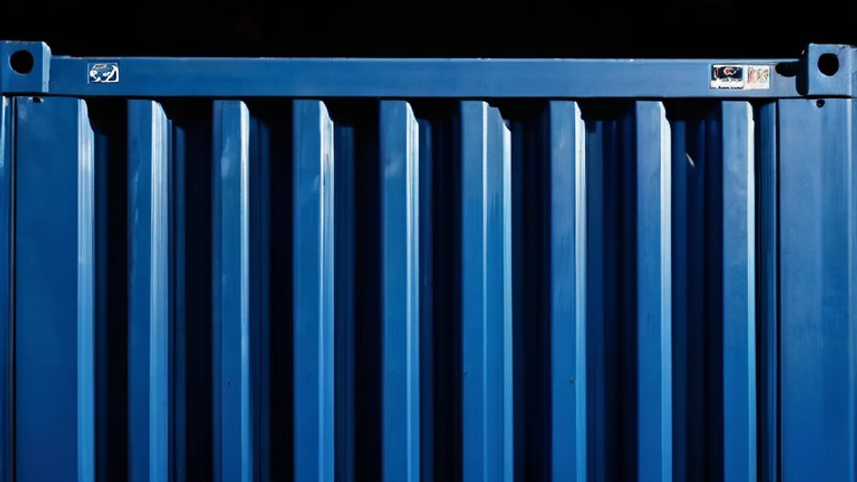 The corrugated steel wall of a shipping container, close up in deep blue light.