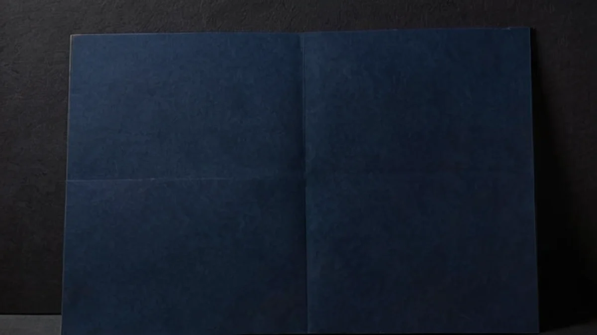 A folded sheet of dark navy card standing on a dark surface.