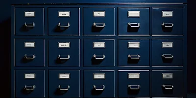 Rows of identical navy archive drawers with blank label holders, in cool light.